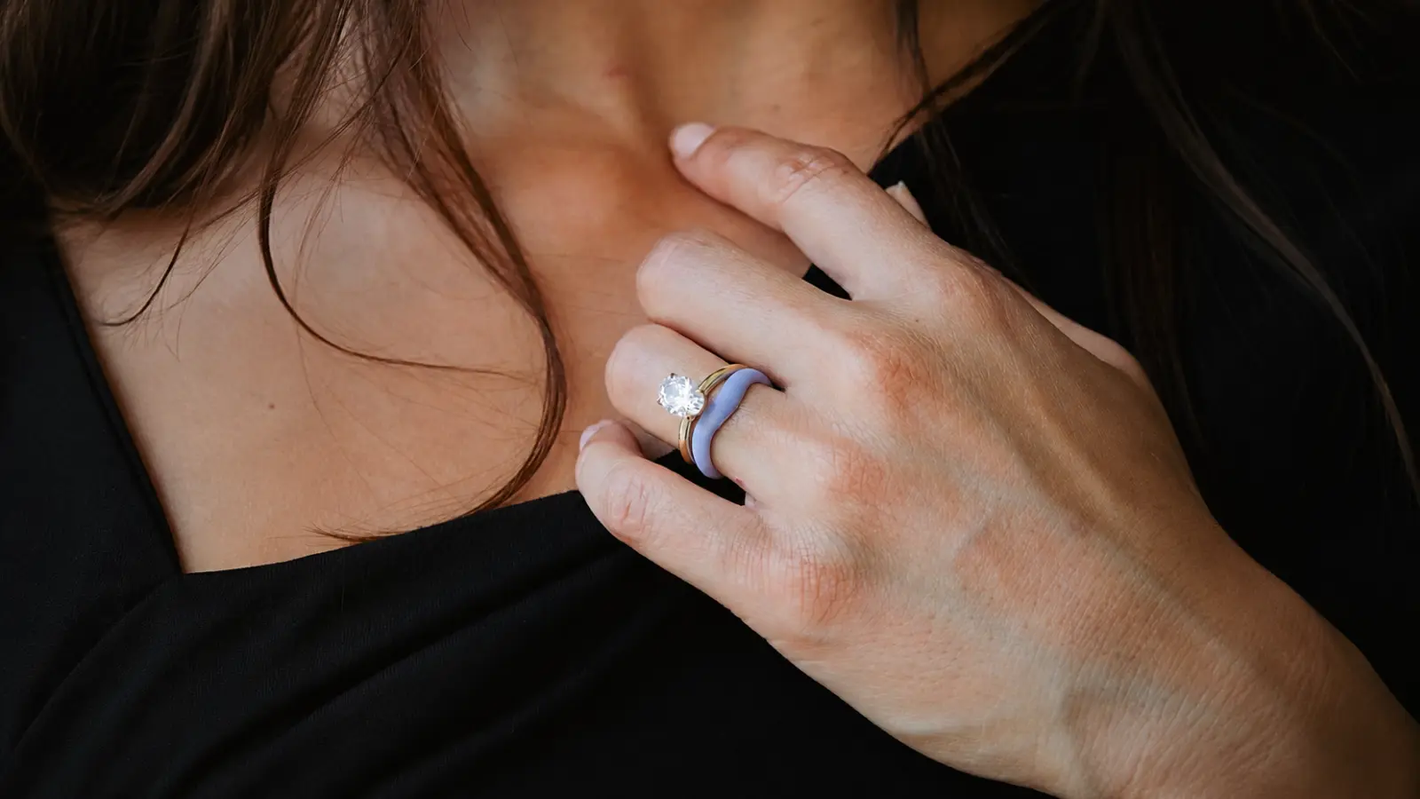A woman wears a silicone wedding ring stacked with a diamond engagement ring, illustrating a safe and comfortable choice for everyday wear