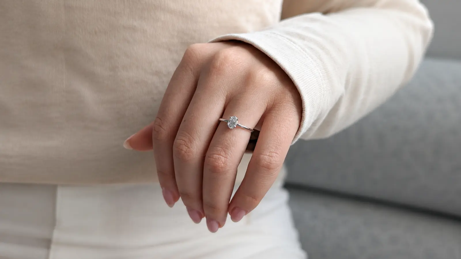 A close-up of a hand wearing a silver solitaire engagement ring, highlighting the polished band, sparkling center diamond and timeless minimalist design