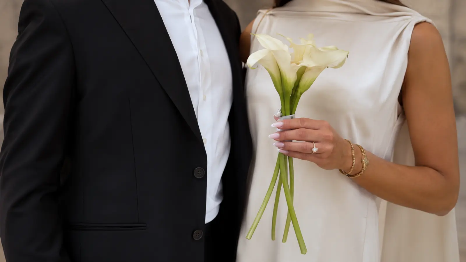 Bride holding a simple white calla lily wedding bouquet beside her partner