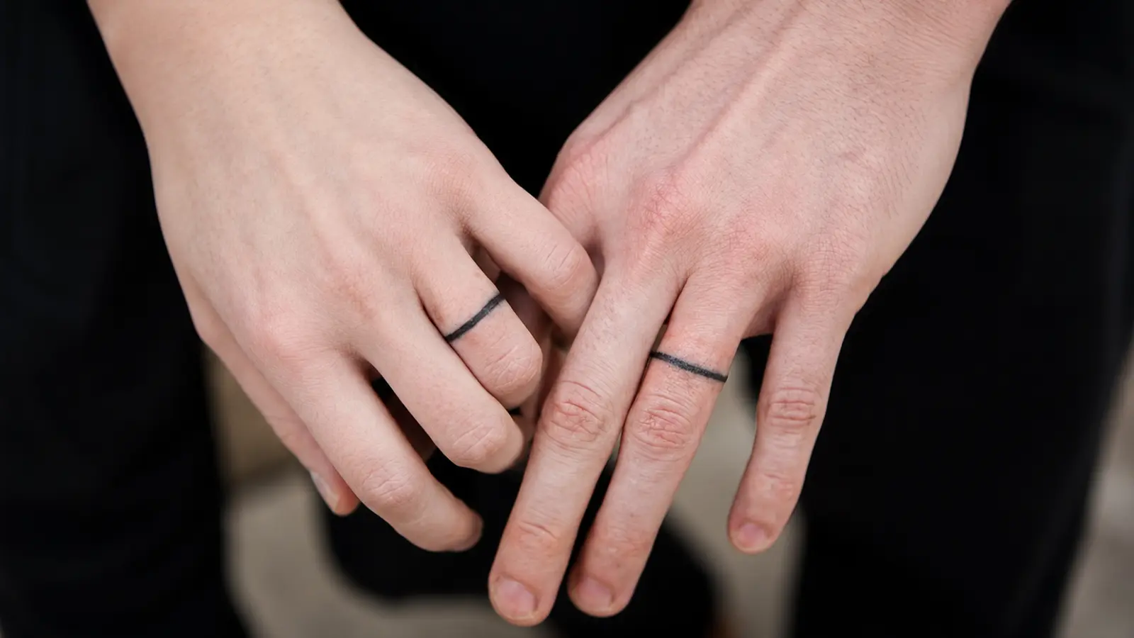 Close-up of matching simple wedding ring tattoos on a couple's hands