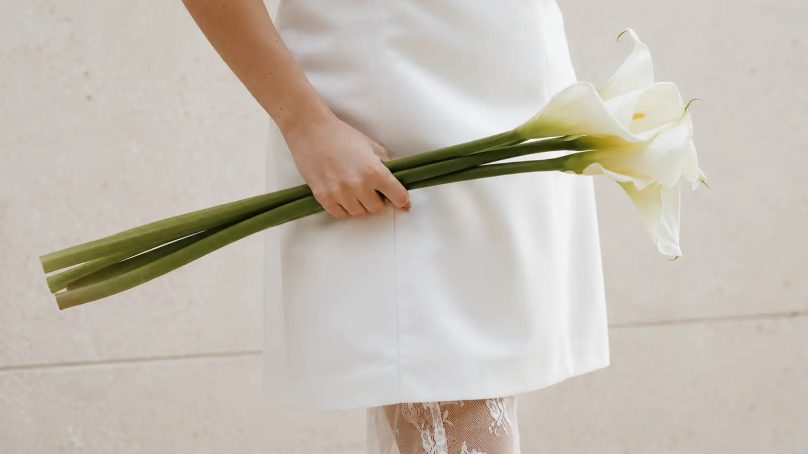 Bride holding a simple bouquet made with three elegant white calla lily stems