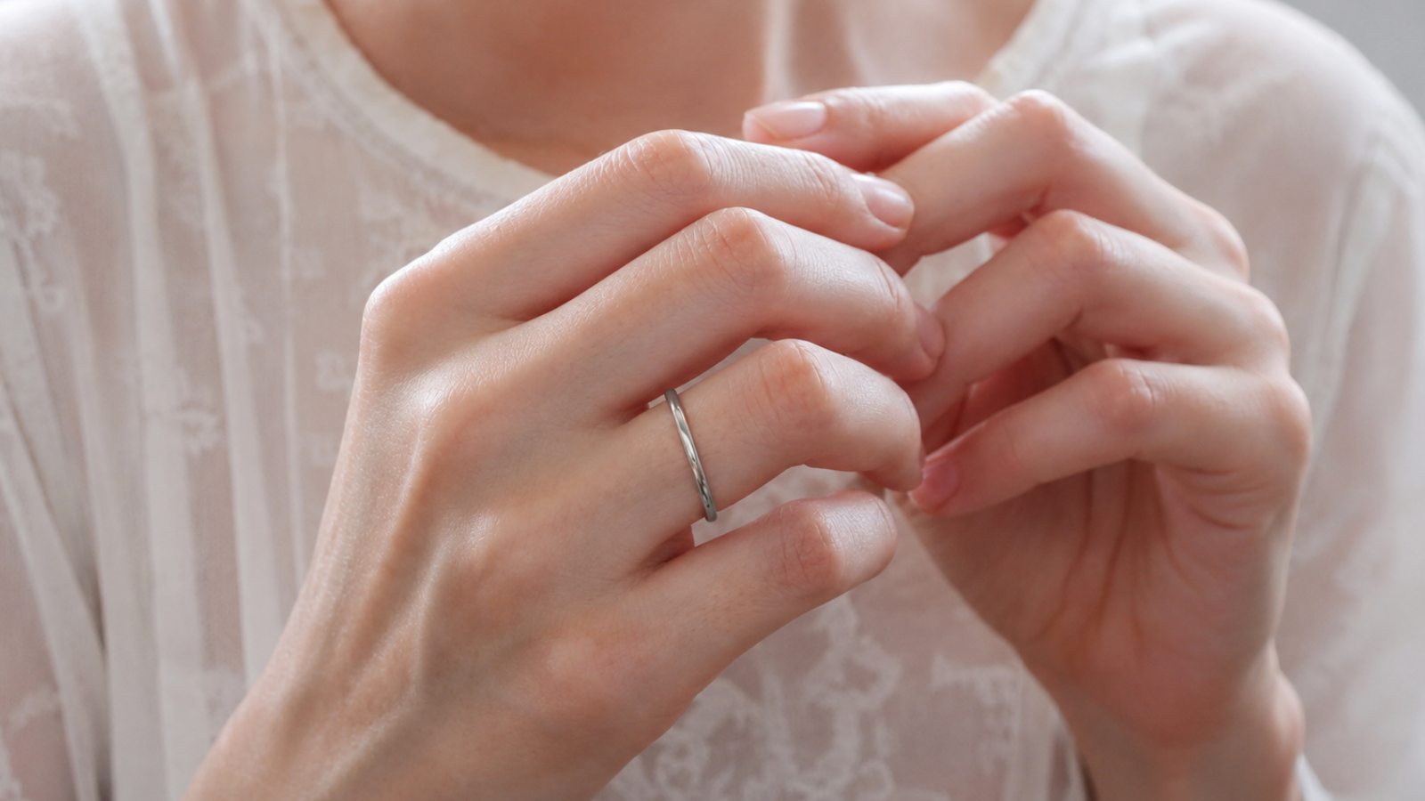 Woman wearing a slim silver minimalist wedding band on her finger, demonstrating a modern elegant and understated wedding ring for everyday wear