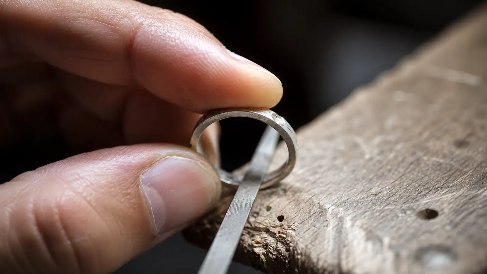 A jeweler filing the edge of a wedding ring during the resizing process to create a smooth and even finish