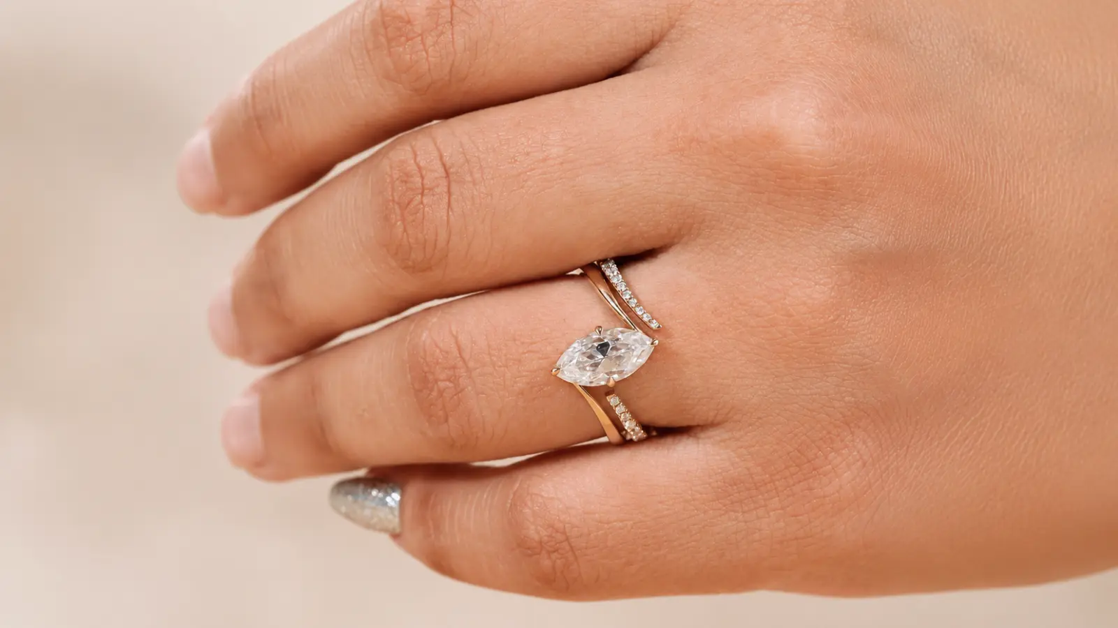 A marquise engagement ring paired with a split curved diamond wedding band in a stacked bridal set