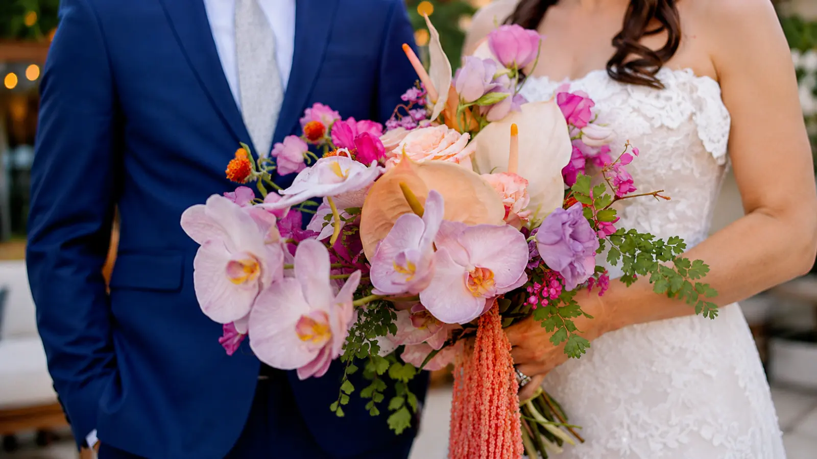 Bride holding a summer wedding bouquet with pink orchids, anthuriums, roses and tropical seasonal flowers