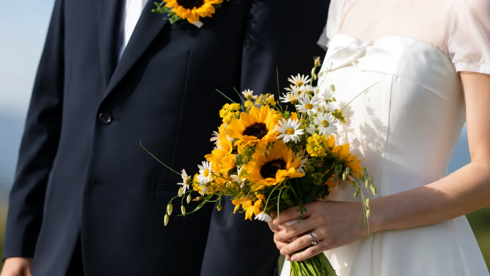 Bride holding a rustic sunflower wedding bouquet with daisies