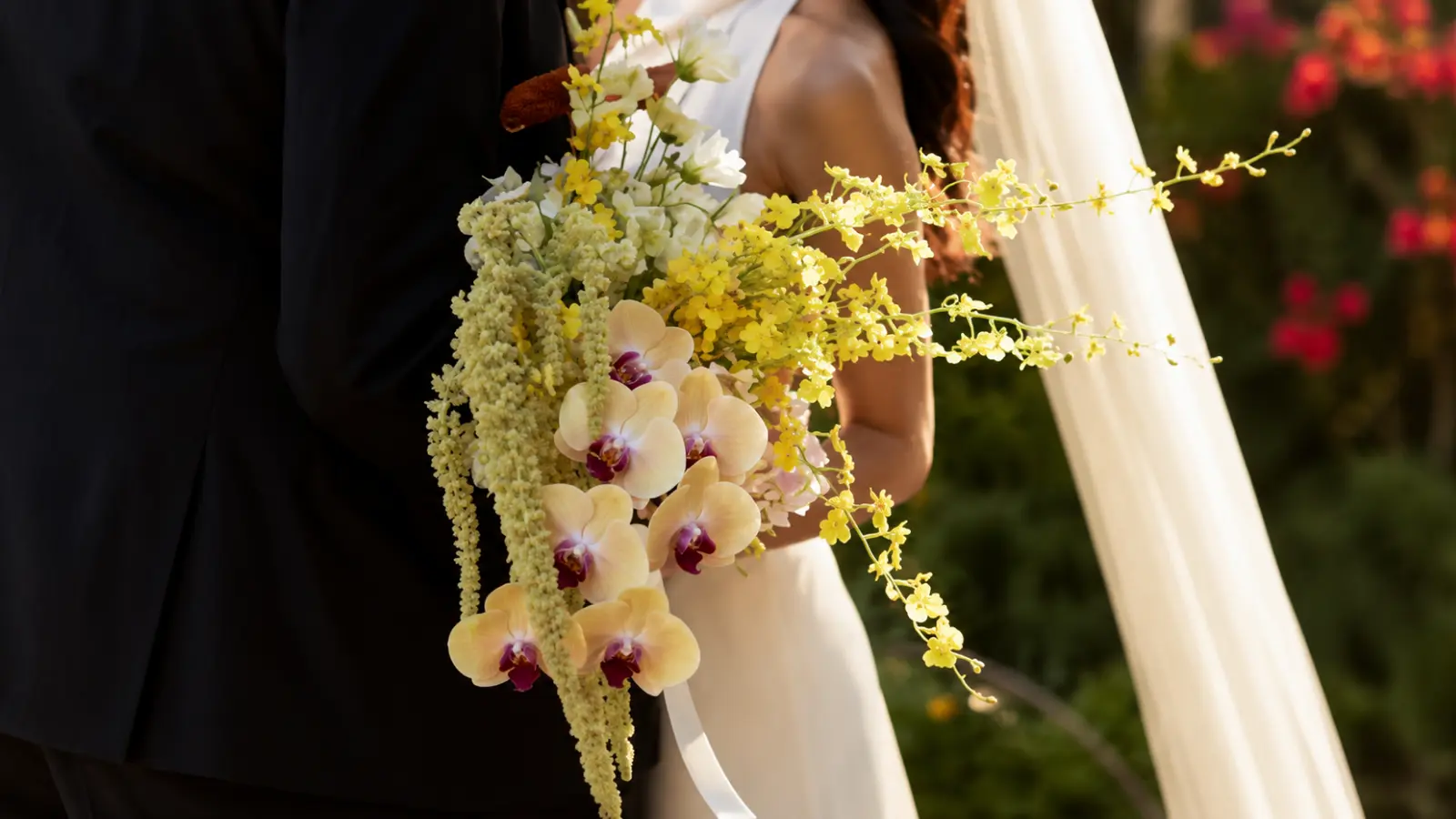 Bride holding a tropical orchid wedding bouquet with yellow phalaenopsis orchids, oncidium orchids, and cascading blooms