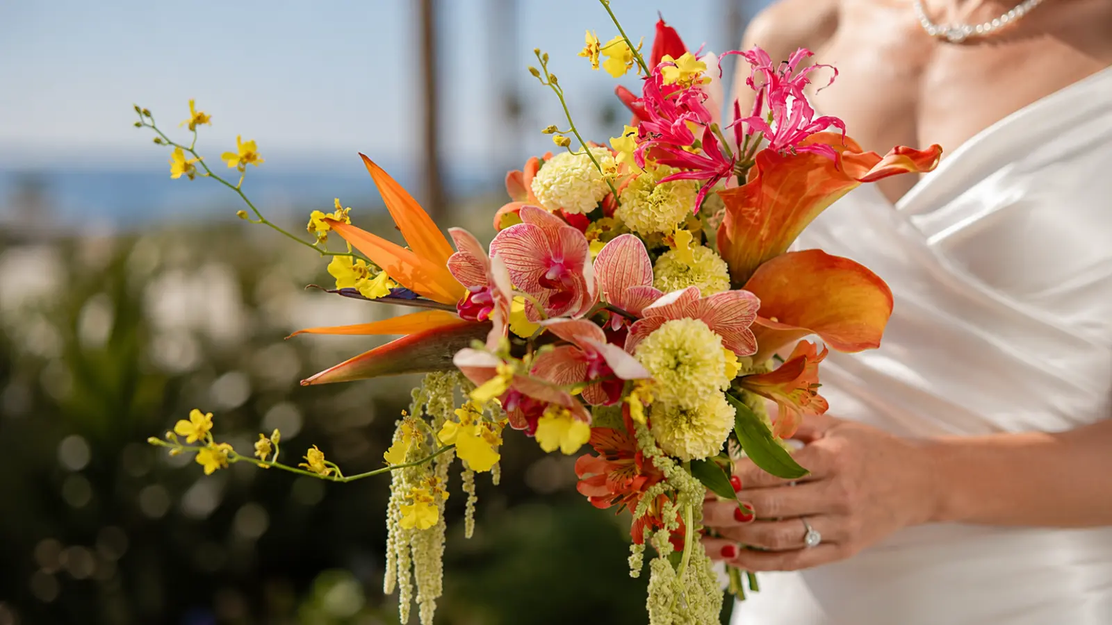 Bride holding a tropical spring wedding bouquet with orchids, calla lilies and colorful exotic flowers