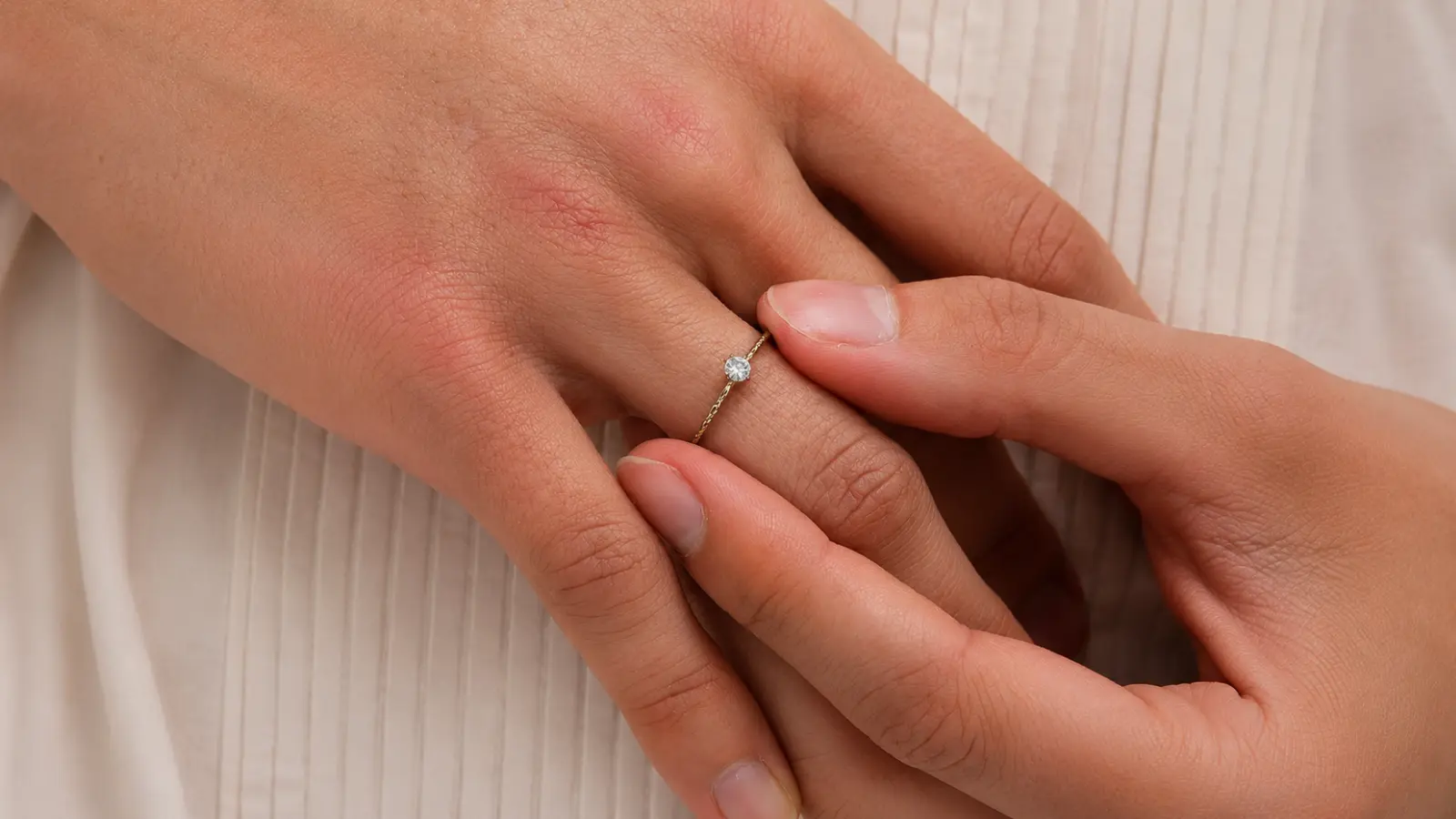 Hands gently adjusting an ultra-thin minimalist wedding rings with a small solitaire diamond on a delicate gold band