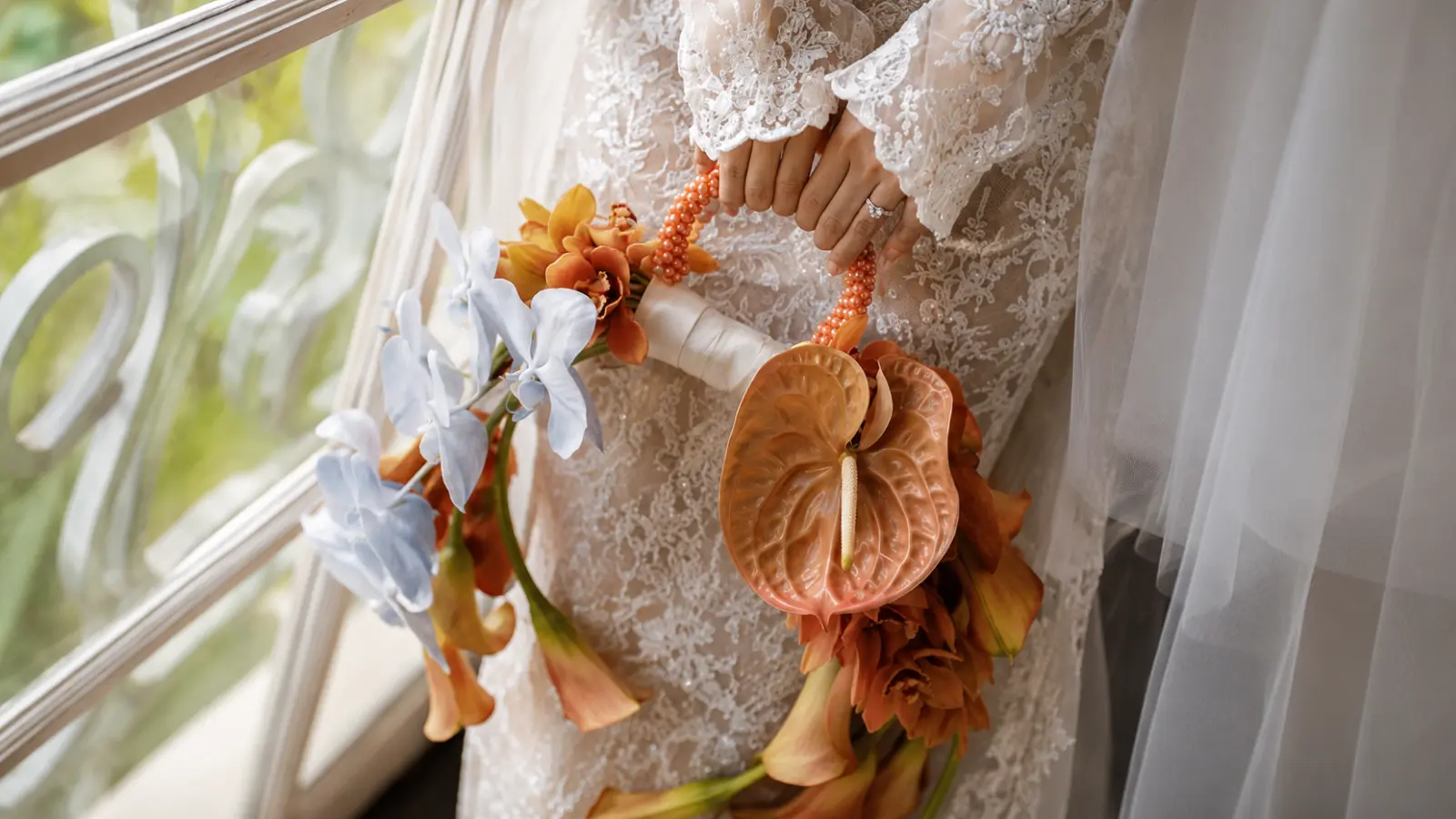 Bride holding a unique loop handle wedding bouquet with orchids and anthurium
