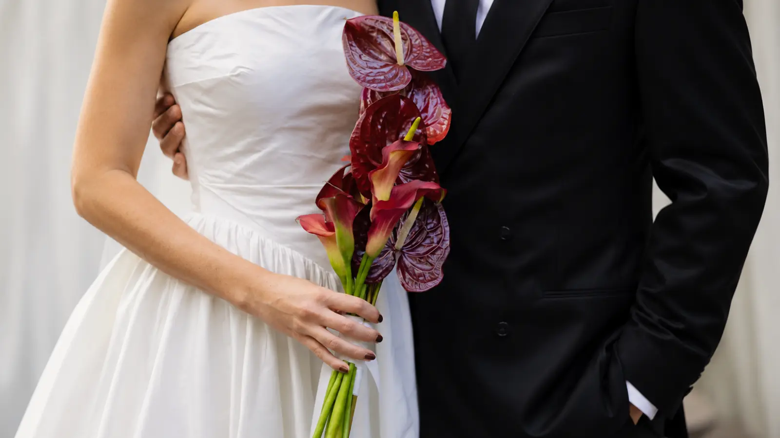 Bride holding a vertical bridal bouquet with burgundy anthuriums and calla lilies