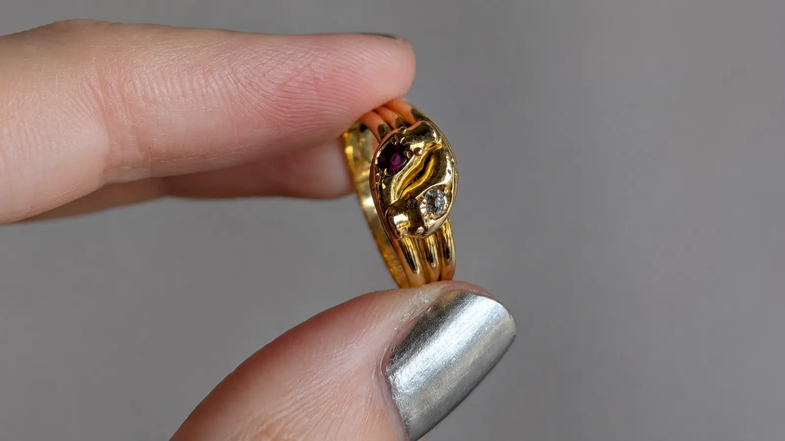 A close-up of a Victorian-inspired vintage wedding ring with ruby and diamond accents set in an ornate yellow gold design