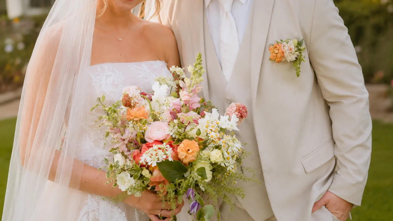 Bride with a pastel wedding bouquet standing beside the groom wearing a matching floral boutonniere