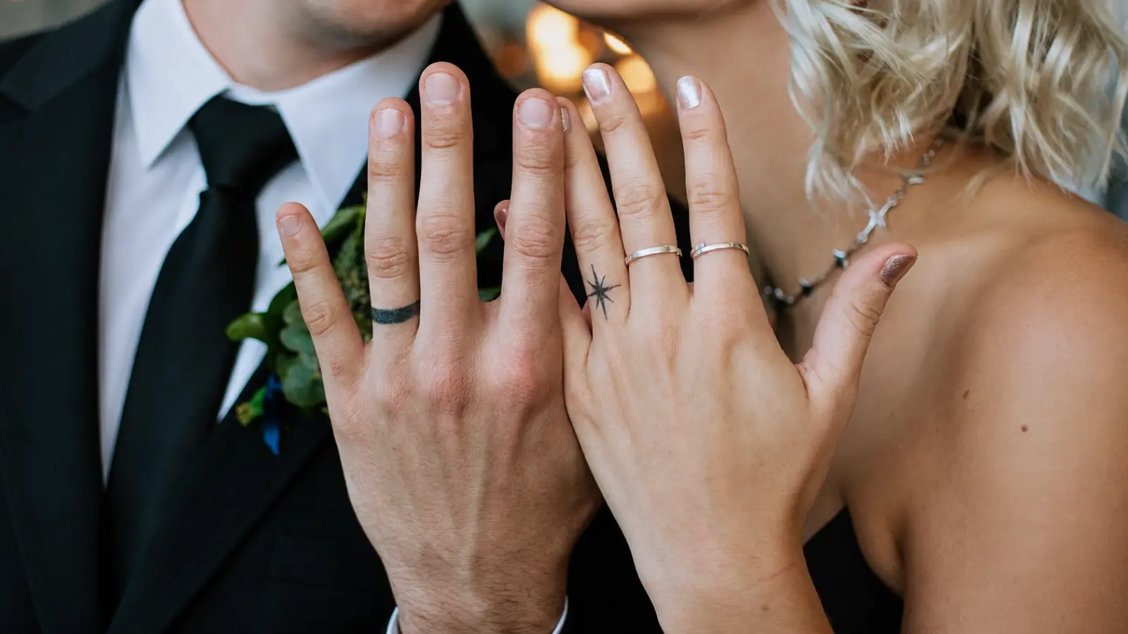 A couple wearing wedding ring tattoos alongside traditional wedding rings on their hands