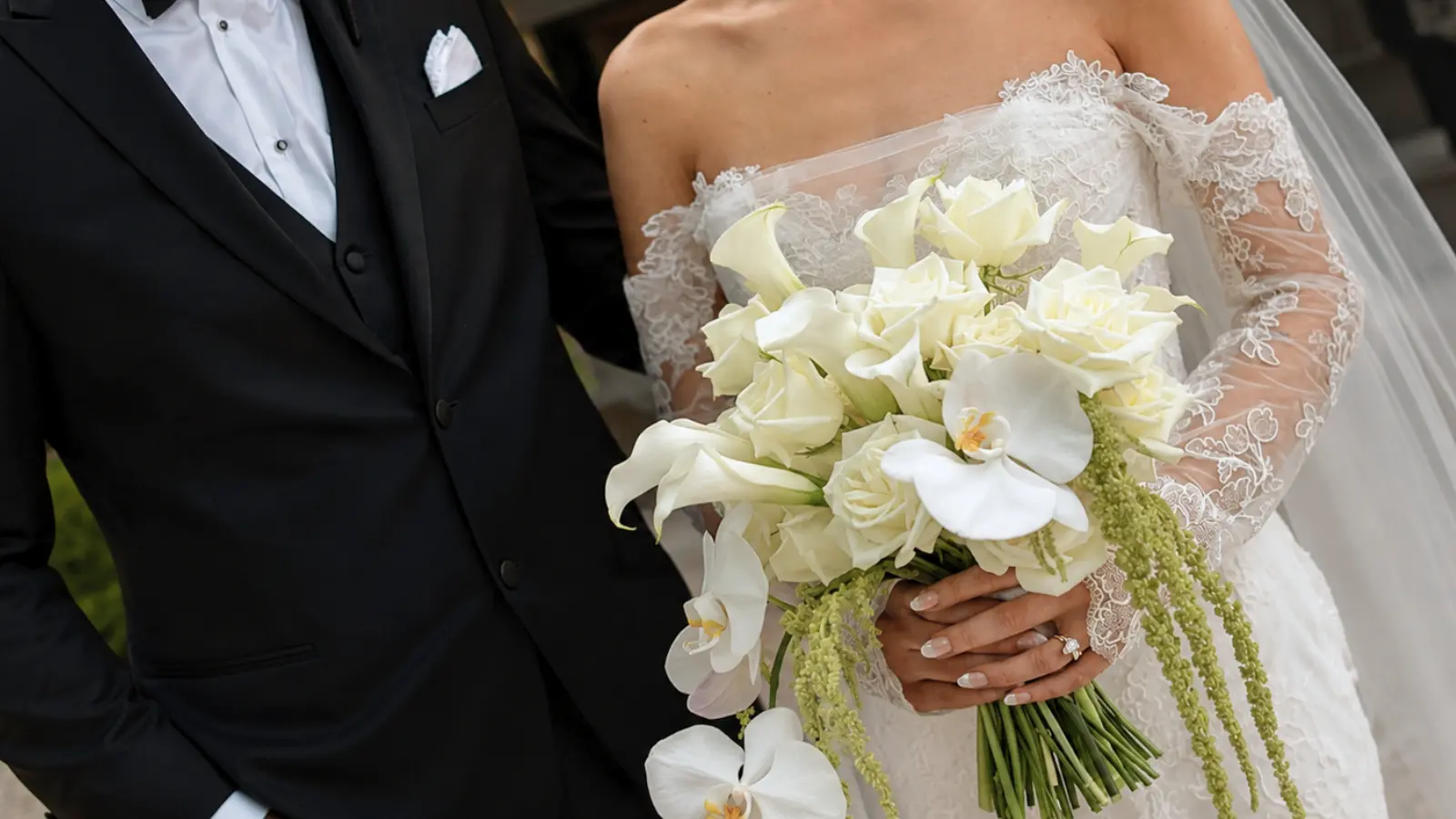 Bride holding an elegant white wedding bouquet with calla lilies, orchids and roses