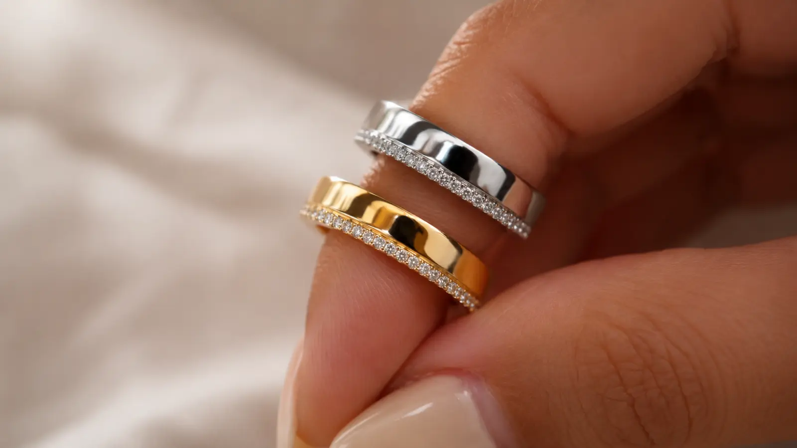 A polished white gold wedding ring sits beside a yellow gold wedding ring, clearly demonstrating the contrast in color, brightness and overall appearance between these popular wedding band metals