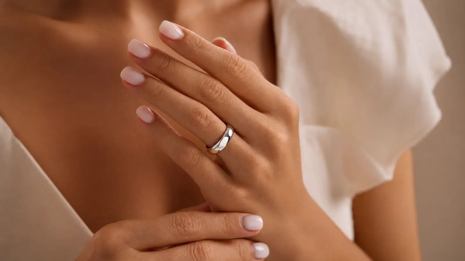 Simple white gold wedding band worn on a woman's hand