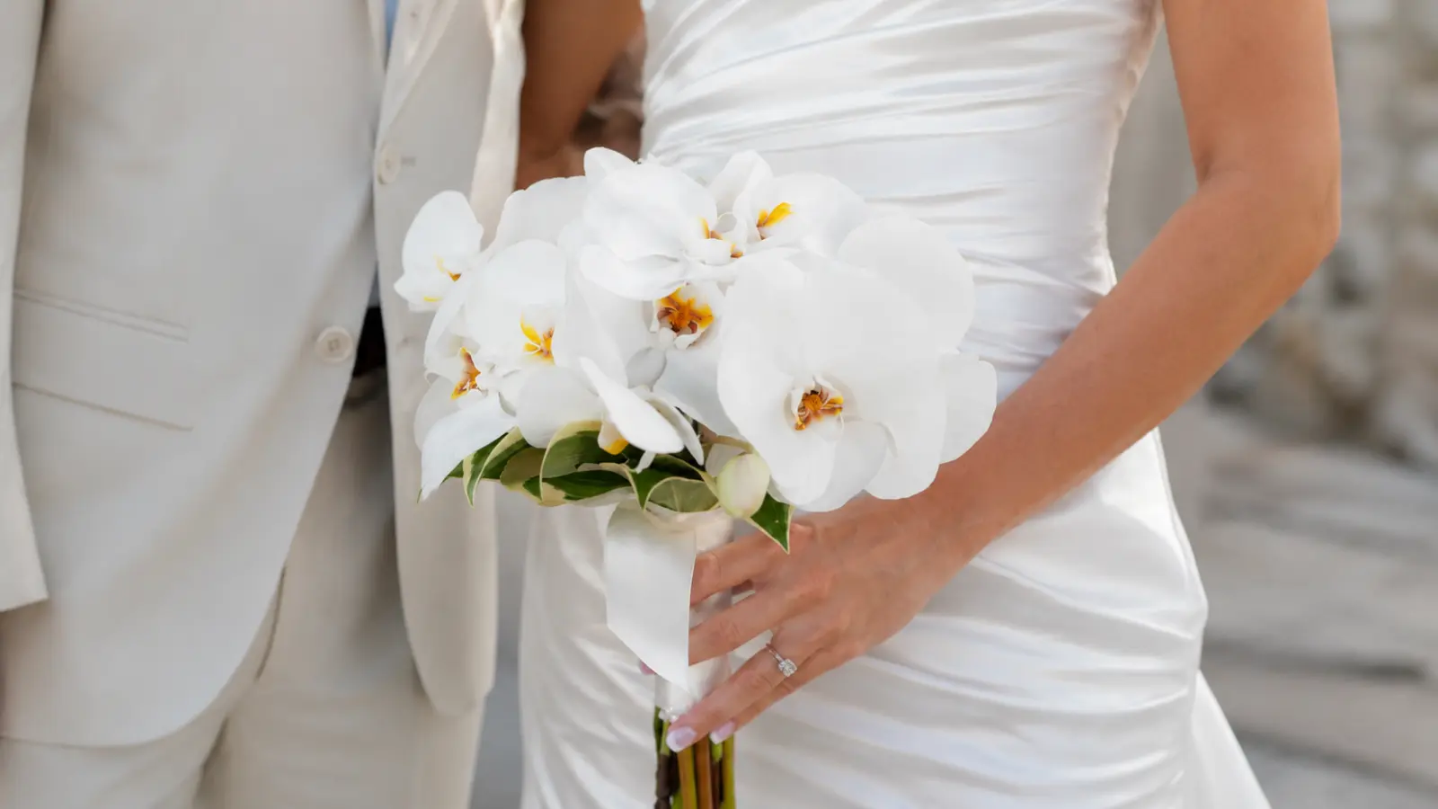 Bride holding a white Phalaenopsis orchid wedding bouquet with satin ribbon
