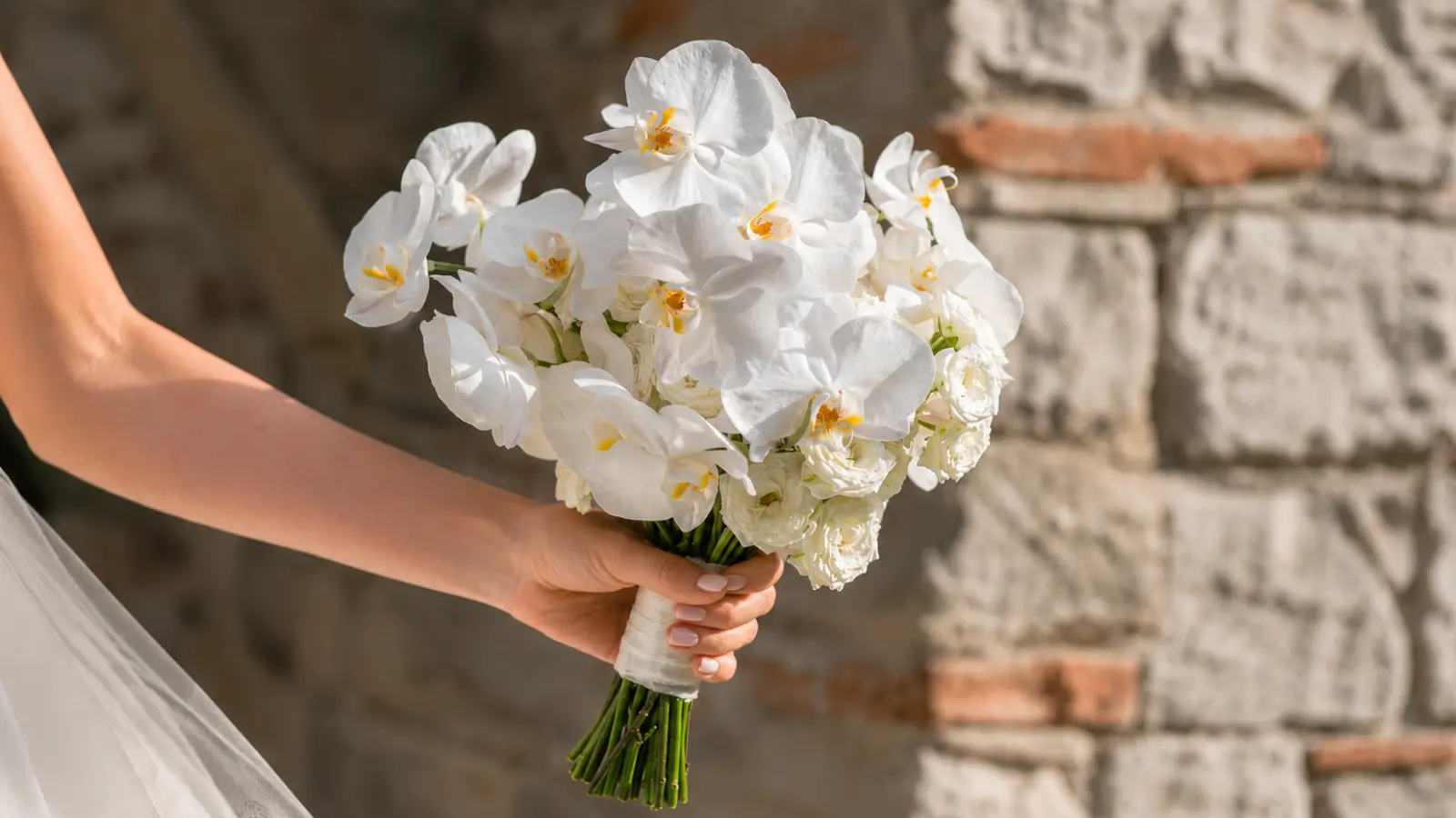 Bride holding a white phalaenopsis orchid wedding bouquet with white garden roses