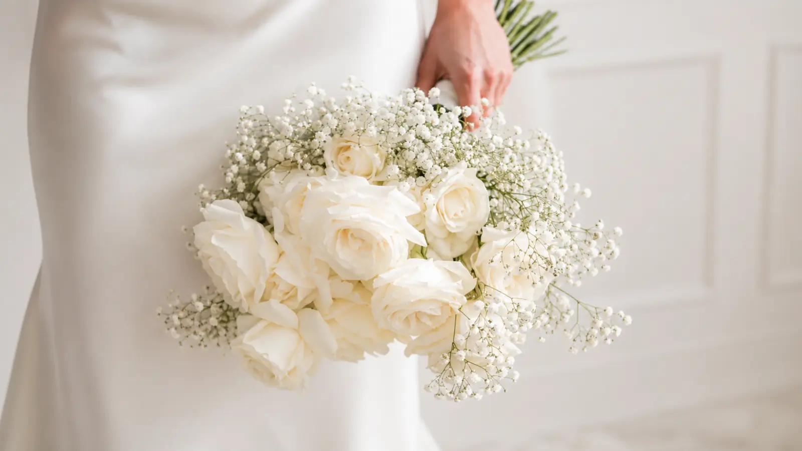 Bride holding an elegant wedding bouquet made of white roses and baby's breath flowers