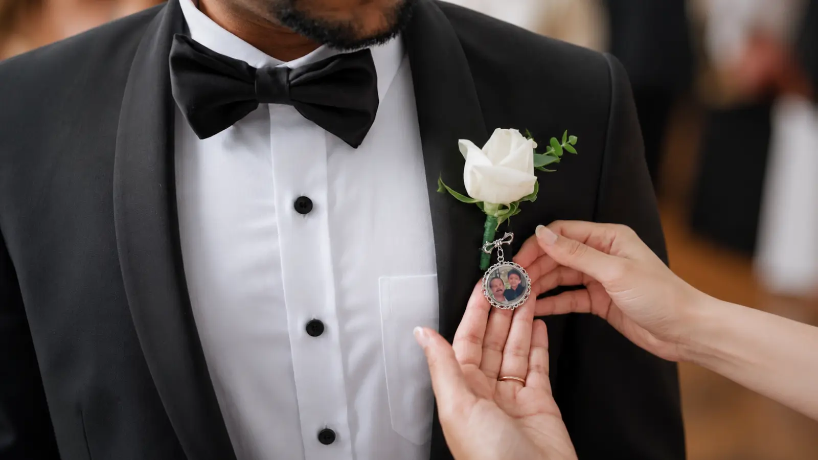 Groom wearing a white rose boutonniere with a memorial photo charm attached beneath the flower