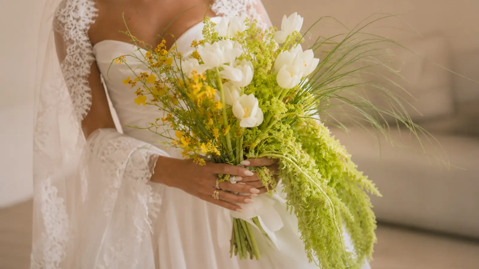 Bride holding a white tulip and greenery cascading wedding bouquet with flowing fresh foliage and elegant white blooms
