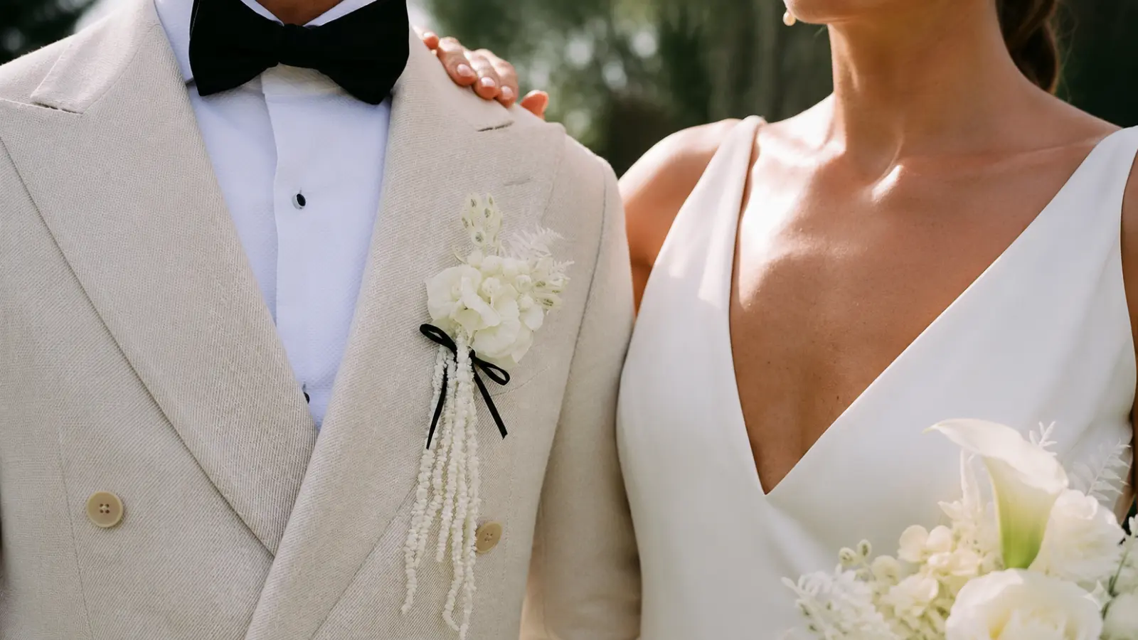 Bride with a white bouquet beside the groom wearing a matching cascading white boutonniere