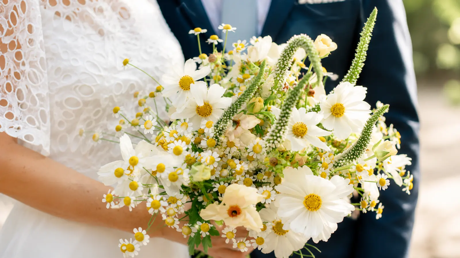 Close-up of a white wildflower wedding bouquet featuring cosmos, chamomile, and airy garden flowers