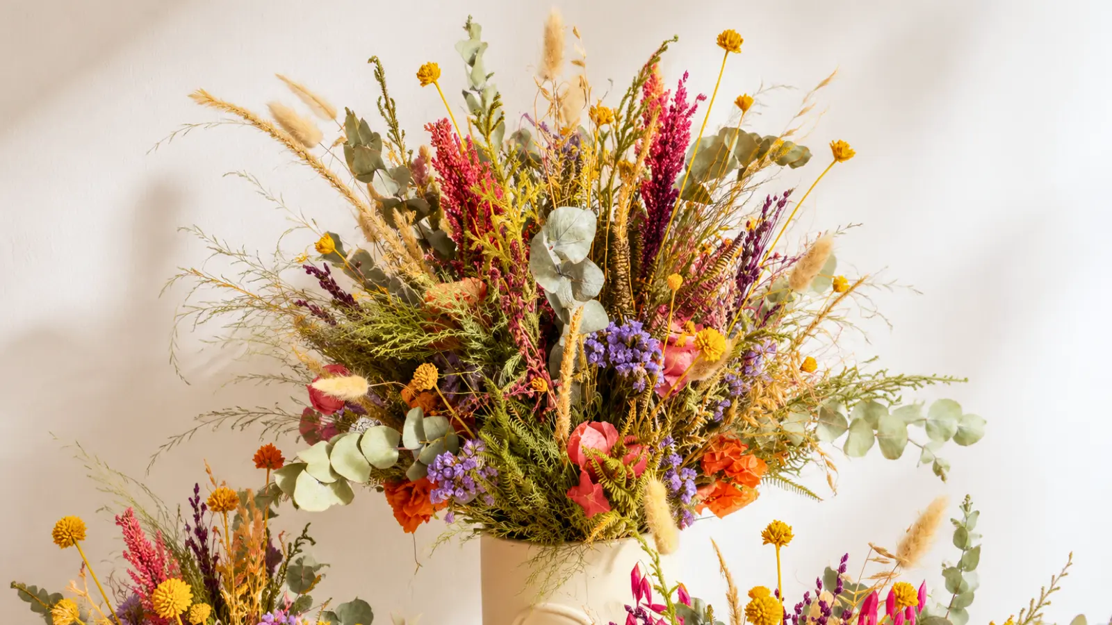 Large floral arrangement featuring colorful wildflowers, dried grasses, eucalyptus, and seasonal meadow flowers
