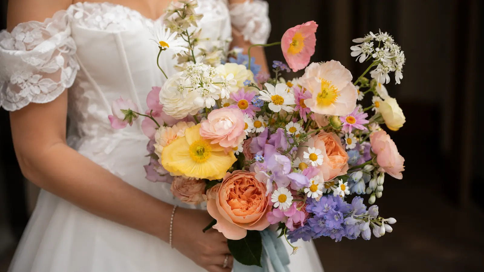 Bride holding a pastel wildflower wedding bouquet with garden roses and poppies