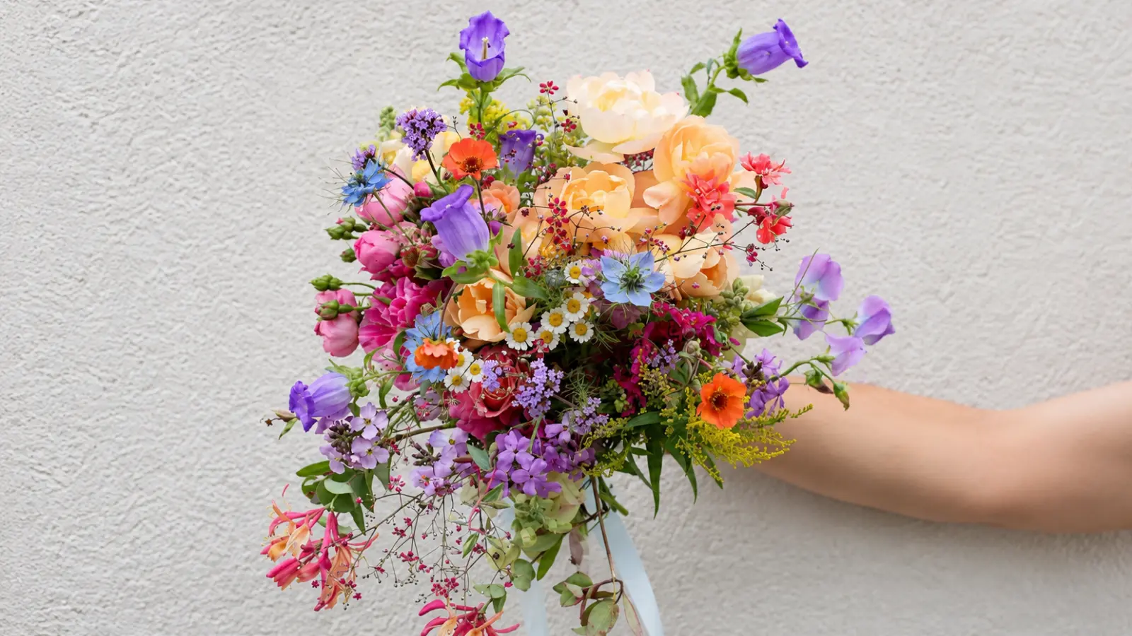 Wildflower summer wedding bouquet with peach roses, campanula and colorful seasonal garden flowers
