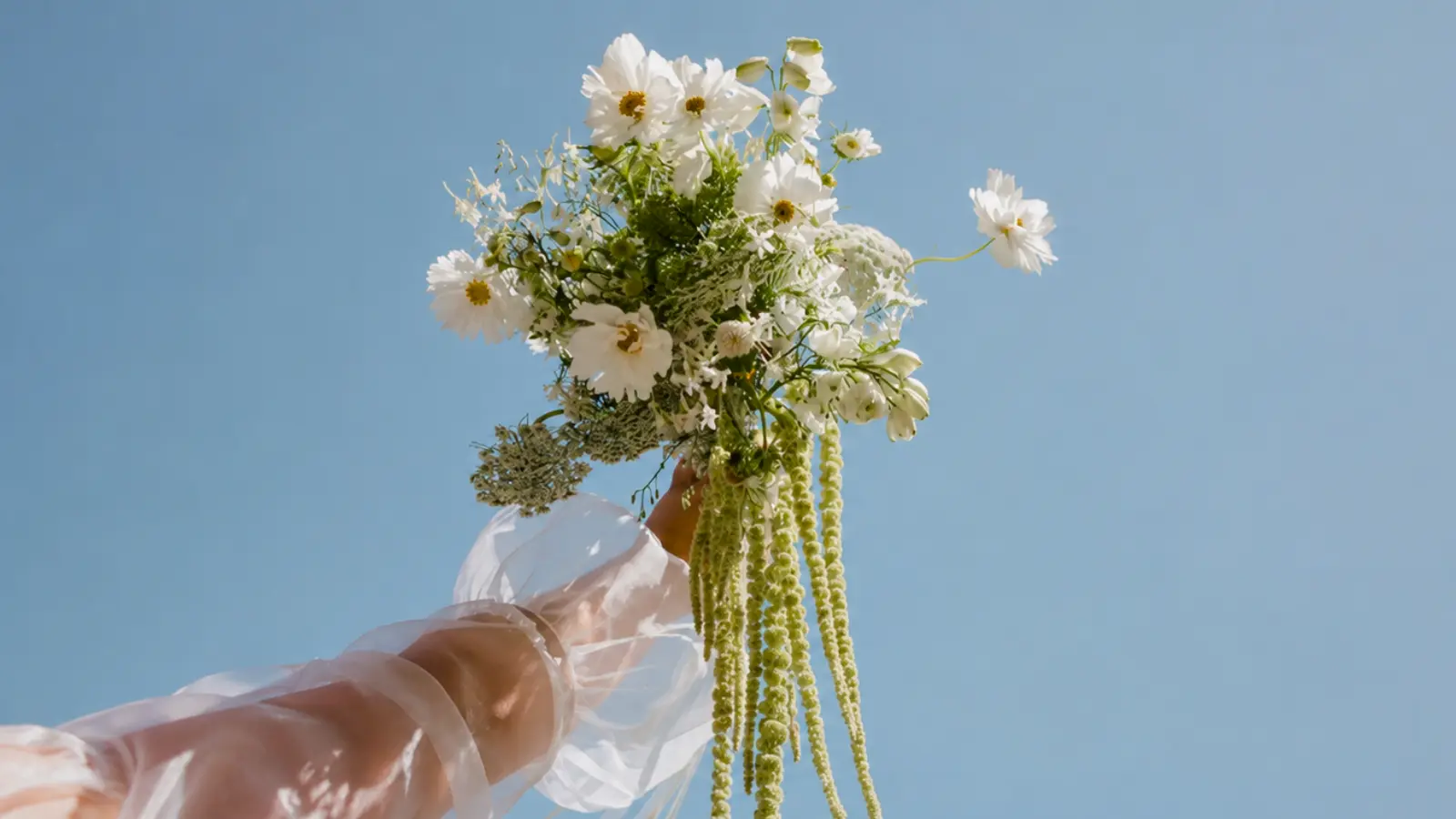 Boho wildflower wedding bouquet held high before the bouquet toss