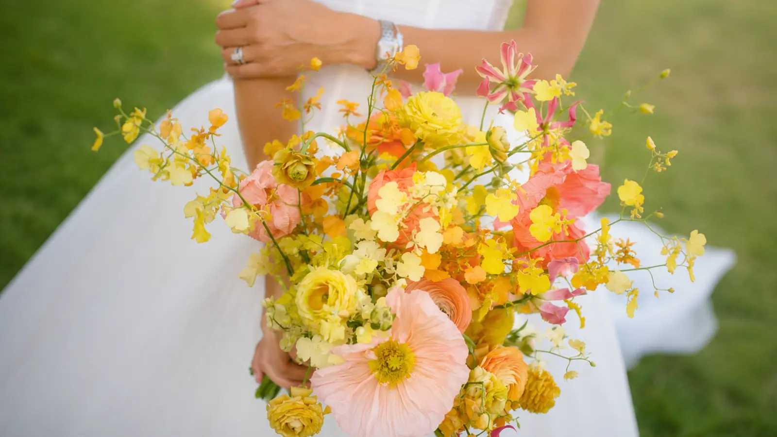 Bride holding a yellow and orange wedding bouquet with poppies and ranunculus