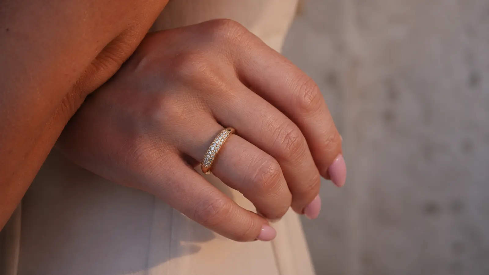 A yellow gold diamond wedding band with pavé-set stones is displayed on a bride's hand, combining sparkling diamonds with the warm and timeless appearance of polished yellow gold