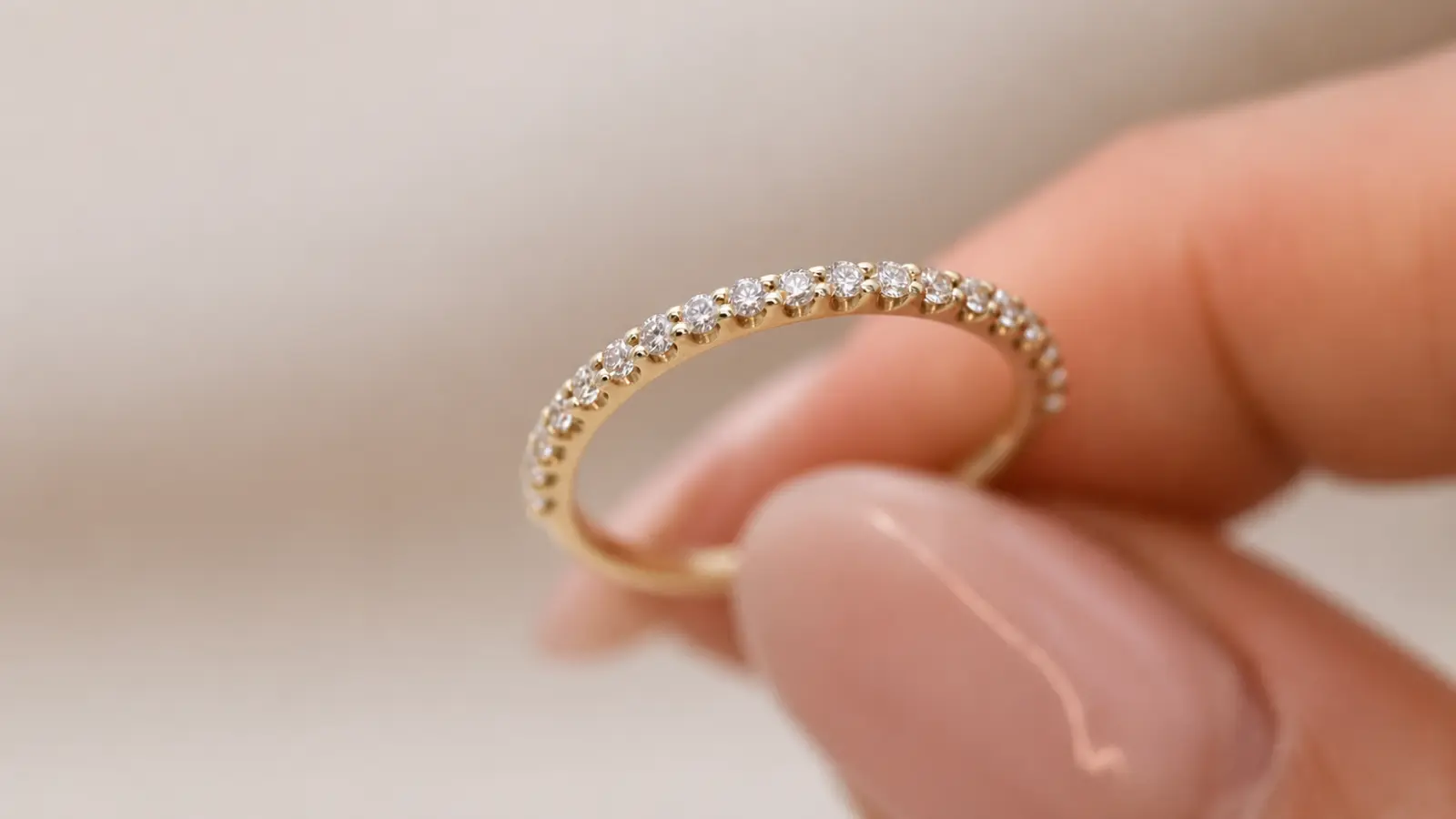 A close-up of a yellow gold pavé diamond wedding band featuring small round diamonds set across the top half of the ring
