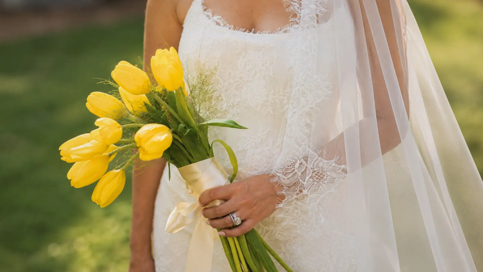 Bride holding a minimalist yellow tulip wedding bouquet wrapped with ivory ribbon