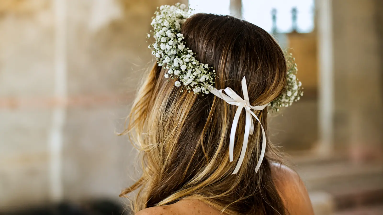 Bride wearing a baby’s breath flower crown with white ribbon and loose waves as a romantic wedding veil alternative Wedding Veil Alternatives