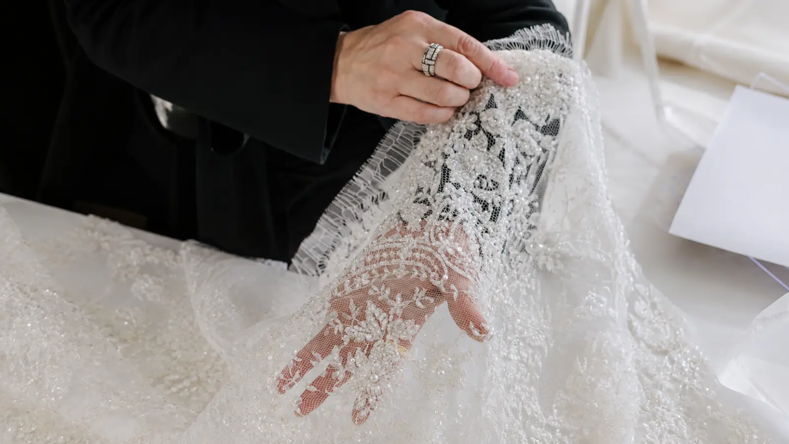 Close-up of heavily beaded lace with pearls and embroidery showing elaborate embellishments that can increase the price of a custom wedding veil