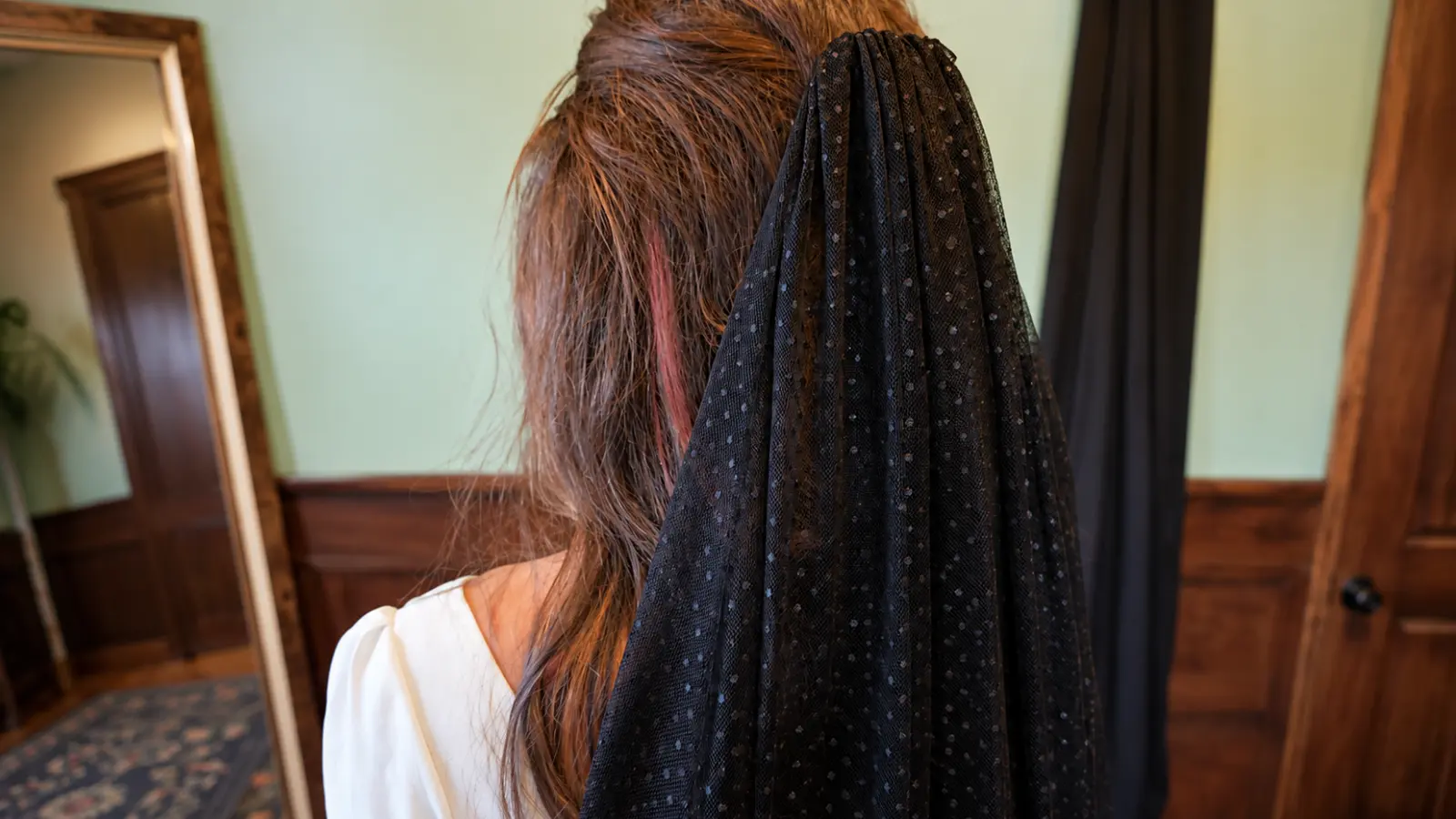 Bride wearing a black colored wedding veils made from sheer dotted tulle attached at the back of her hairstyle