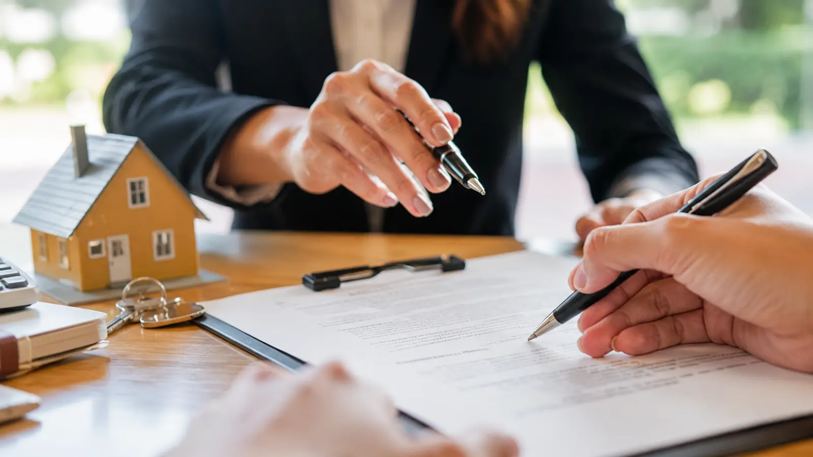 Couple reviewing and signing cohabitation agreement documents with a house model representing shared property and financial arrangements Cohabitation Agreement: What It Is, What It Covers and How It Works