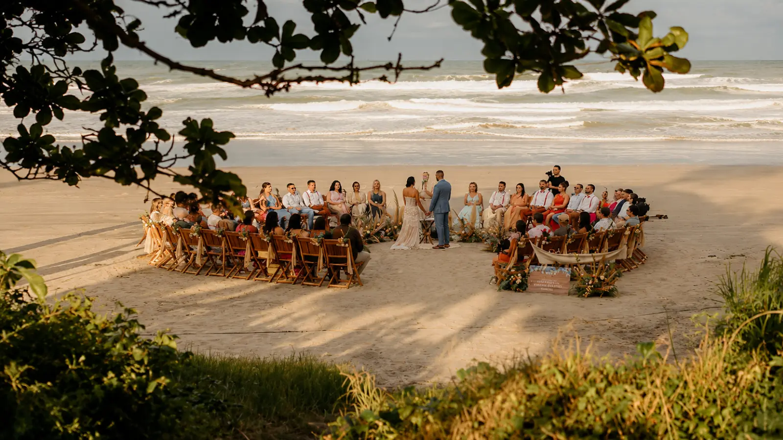 Destination wedding couple exchanges vows on the beach surrounded by invited guests seated in an intimate ceremony arrangement Destination Wedding Guest List: Who to Invite and How to Plan the Count