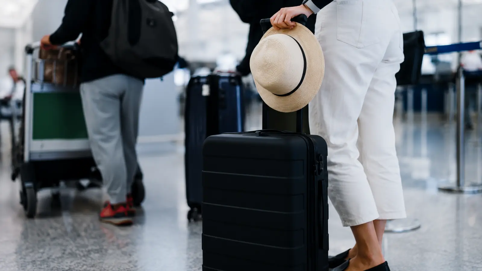 Wedding traveler with suitcase waits at an airport while managing transportation, hotel and guest logistics for a destination wedding Destination Wedding Travel Planning: Hotels, Transportation and Guest Logistics