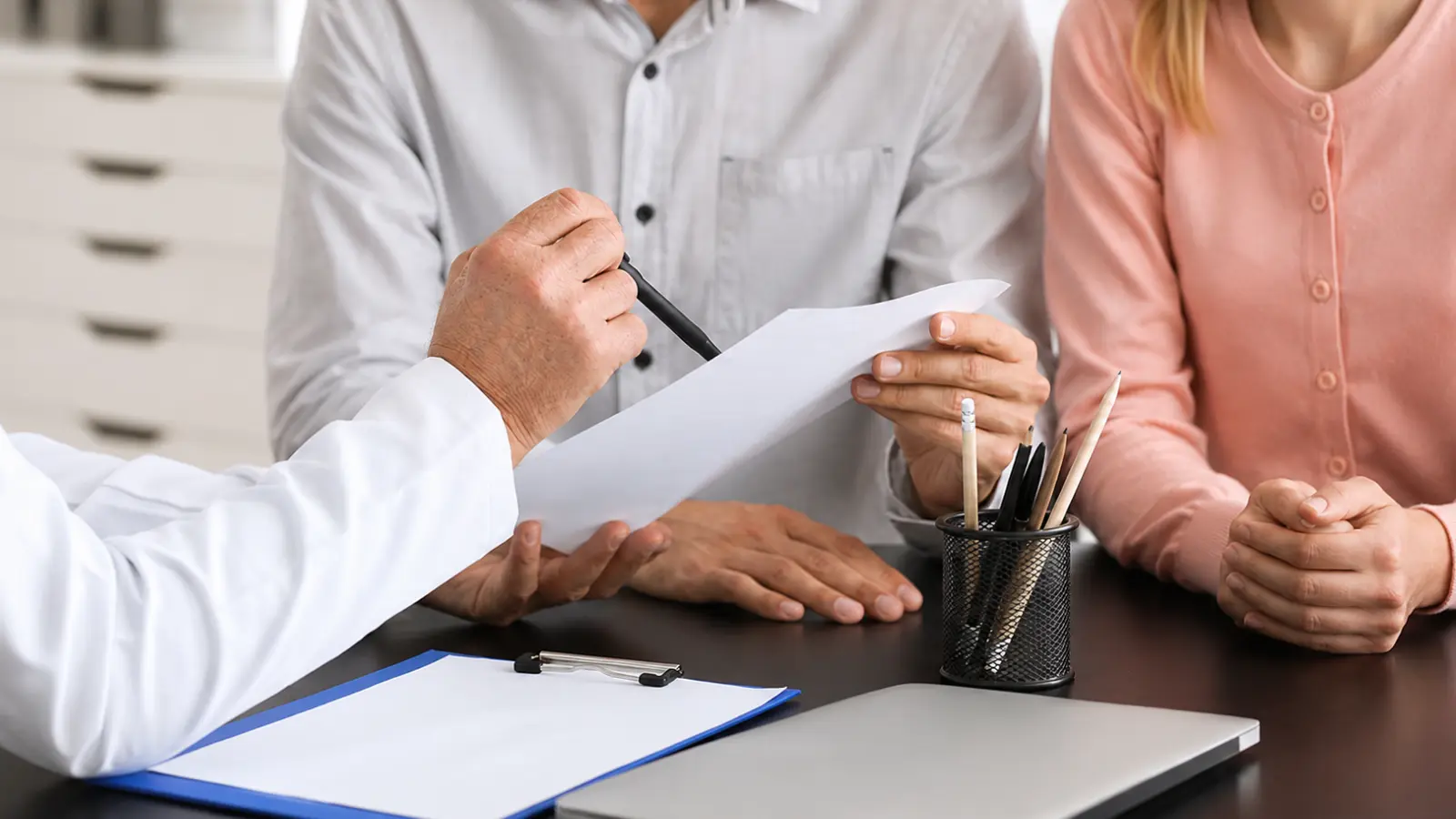 Couple reviewing domestic partnership health insurance documents with a representative to understand eligibility, enrollment requirements, coverage options and costs Domestic Partnership Health Insurance: Eligibility, Enrollment and Costs