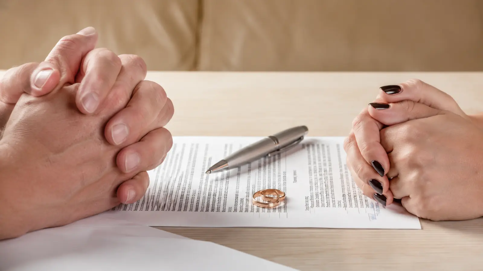 Couple with clasped hands beside divorce paperwork, wedding rings and a pen, illustrating the process, documents and first steps for filing for divorce Filing for Divorce: Process, Documents and First Steps