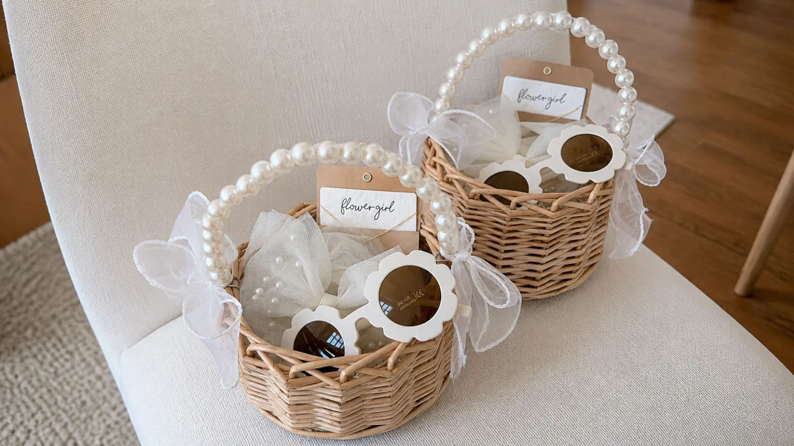 Flower girl gift baskets with pearl handles, white bows, flower sunglasses, jewelry cards, and tulle arranged as personalized wedding gifts