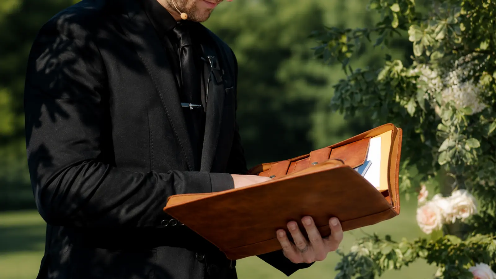 Wedding officiant holding a ceremony binder outdoors while preparing to conduct a wedding, representing legal steps, ceremony duties and officiating requirements How to Officiate a Wedding: Legal Steps, Ceremony and Checklist