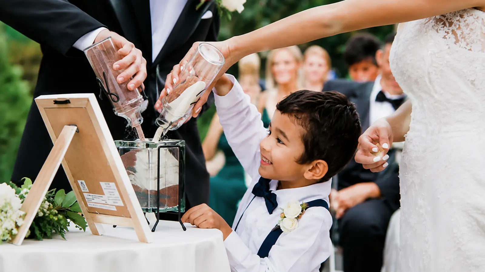 Young boy participates with the couple in a wedding unity ceremony, symbolizing a meaningful way to include children in your wedding day How to Include Your Children in Your Wedding in a Meaningful Way