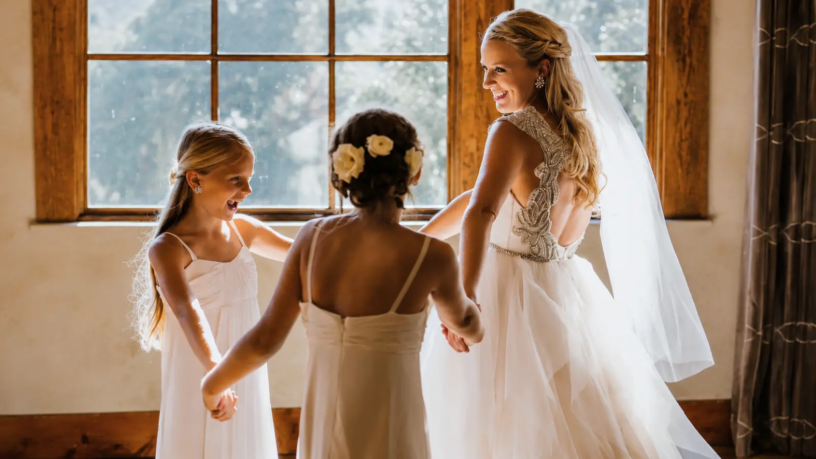 Bride spending time with two junior bridesmaids in white dresses before the ceremony, illustrating how younger attendants can be included in the wedding
