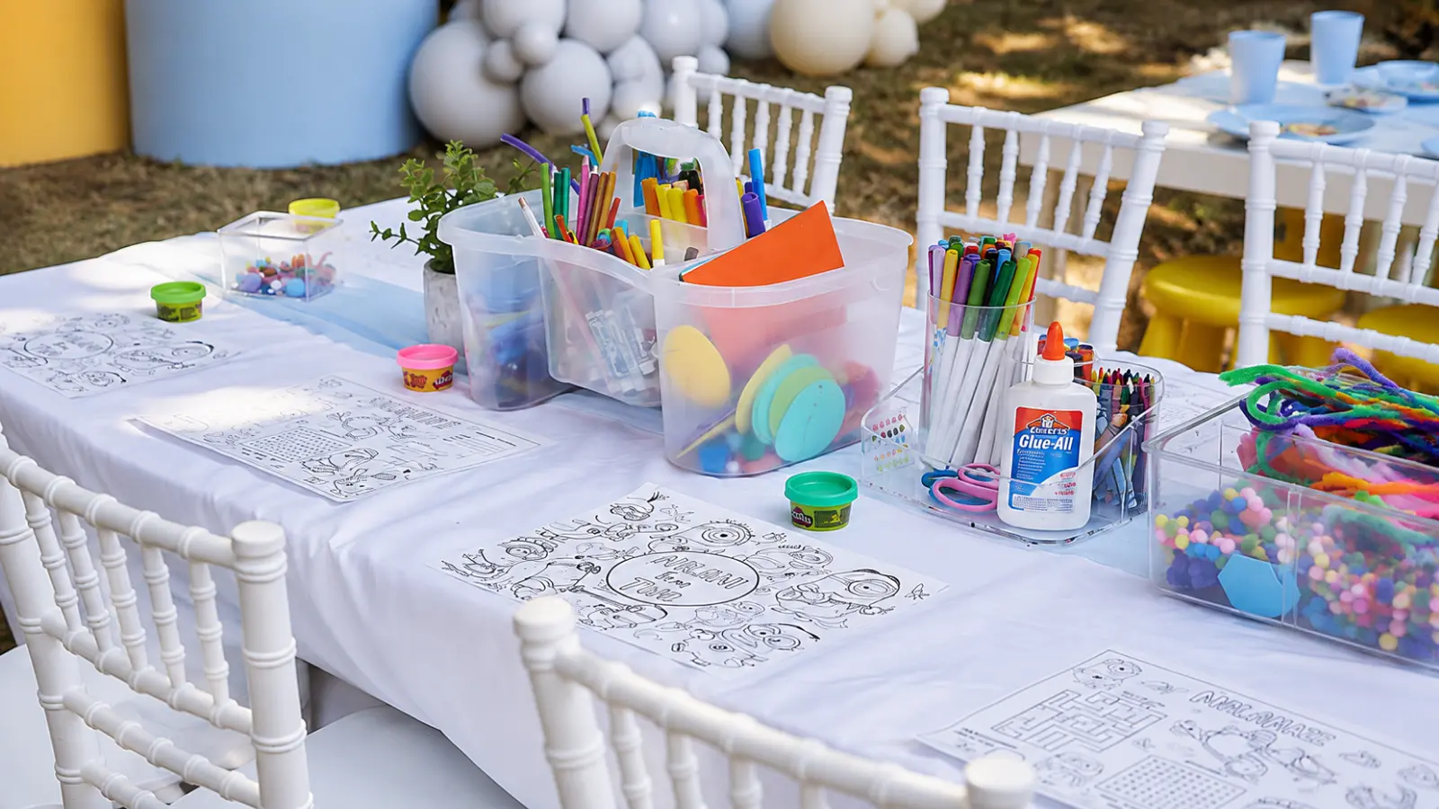Kids table at a wedding filled with coloring pages, markers, crayons, modeling dough, and craft materials for children to enjoy throughout the reception