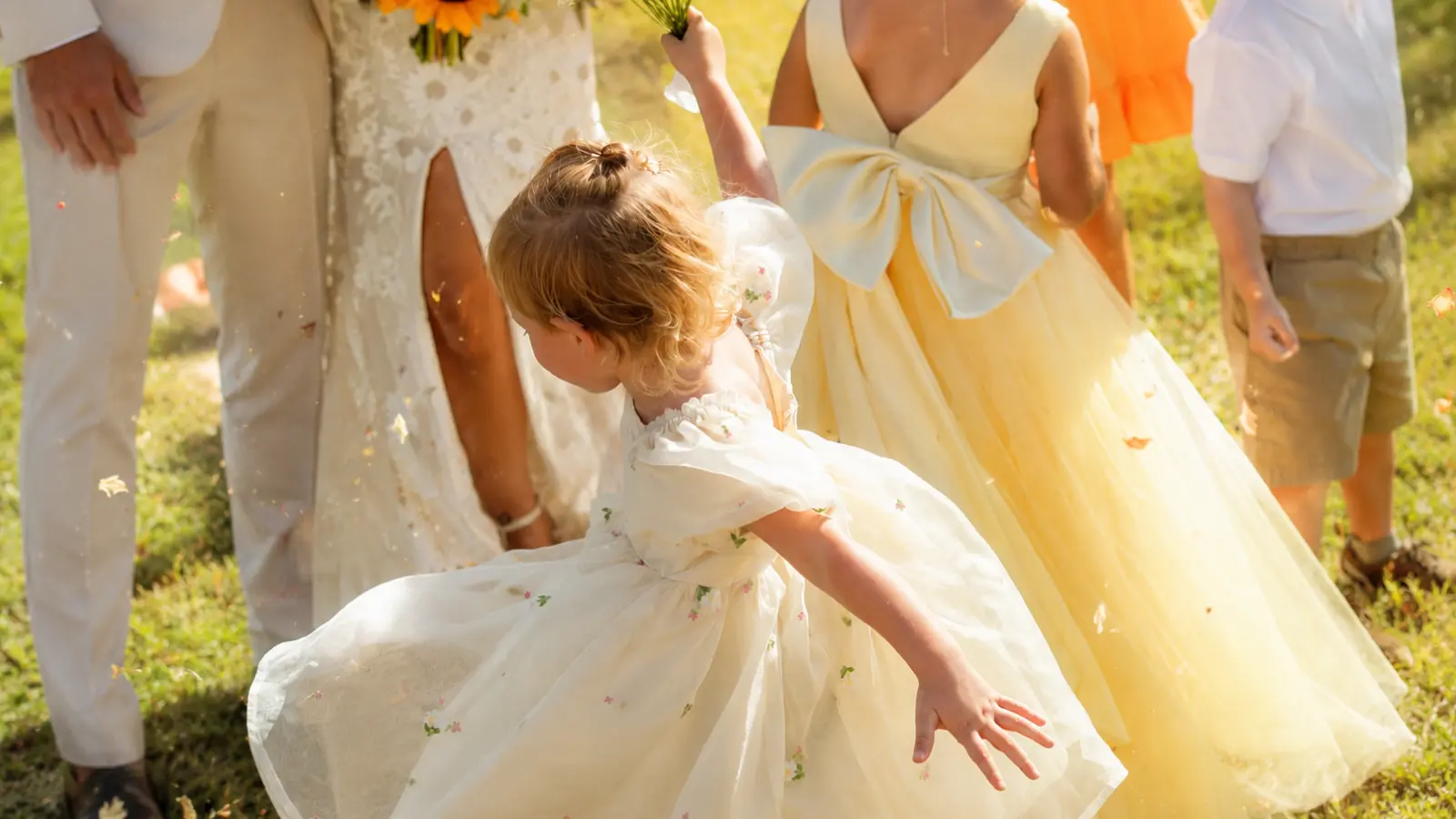 Children wear light dresses and neutral formal clothing outdoors, showing comfortable kids wedding outfits appropriate for a warm-weather wedding dress code